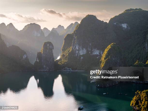 aerial drone sunrise scene of tourist ship with rock mountain on the sea at ha long bay, north of vietnam - halong bay stock pictures, royalty-free photos & images