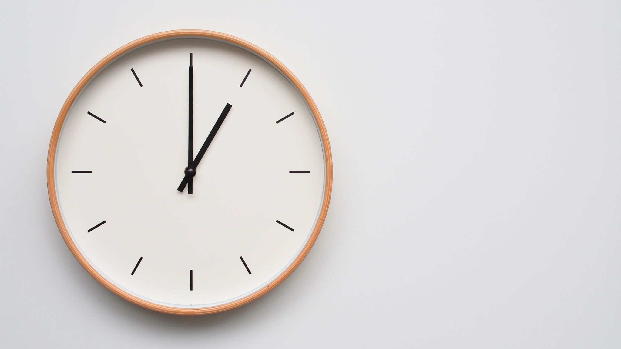 Reloj de pared minimalista de madera sobre superficie de madera blanca con espacio para la hora del texto ajustado a las 13.00/01.00 Reloj de pared minimalista de madera sobre superficie de madera blanca con espacio para la hora del texto ajustado a las 13.00/01.00