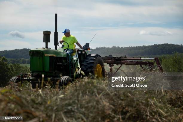 Ken Haas, a third generation farmer, rakes recently cut hay so it will drybefore it is bailed on August 11, 2024 in Elizabeth, Illinois.