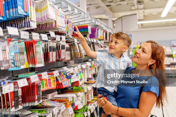 a child excitedly shopping for stationery on his mother's lap - back to school stock pictures, royalty-free photos & images