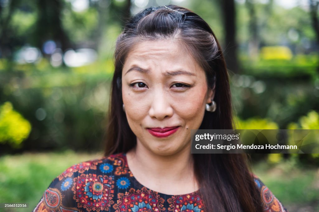 Asian woman raising an eyebrow and looking at the camera, suspicious, curious