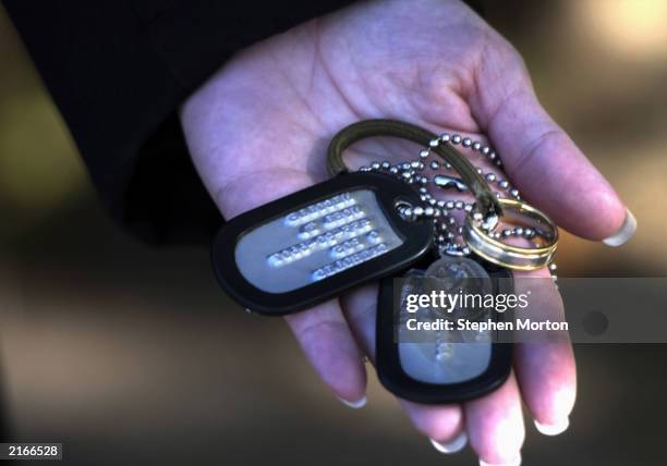 Tamara Nicolle holds a duplicate set of dog tags and small religious medals that her husband, Noel Nicolle, gave to her to wear while he is in the...