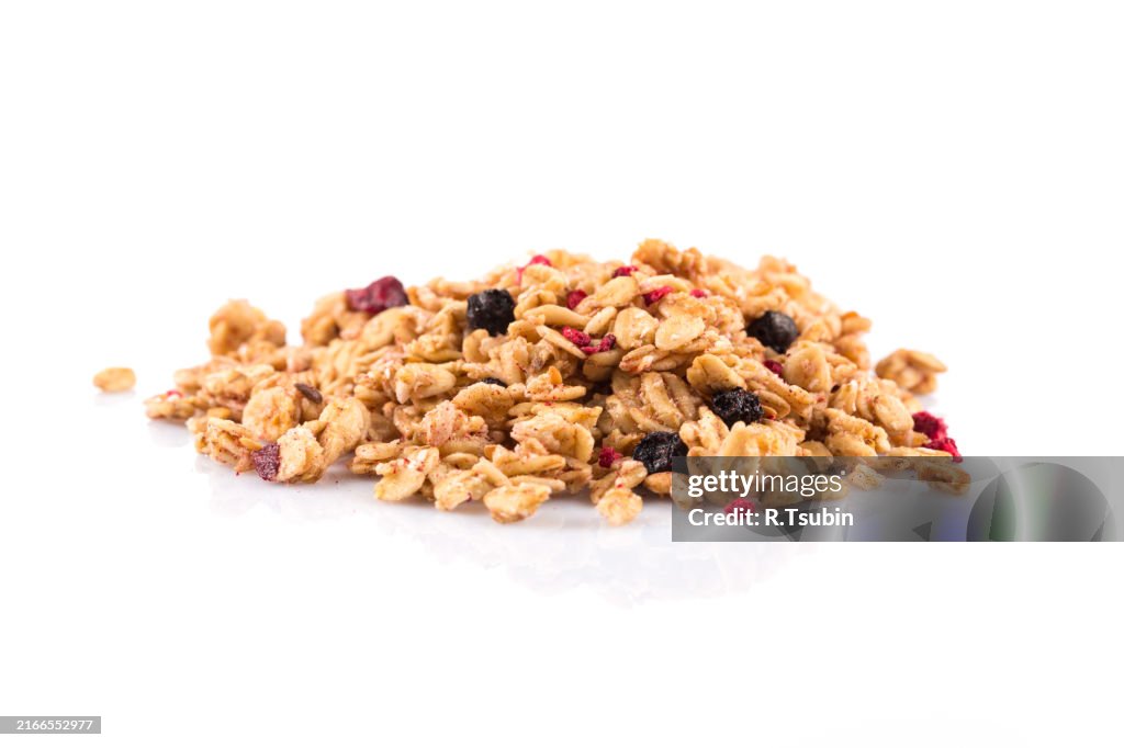 Muesli cereals close up with raisins, oat and wheat flakes, fruits, strawberry, cranberry, cherry pieces. Isolated on white