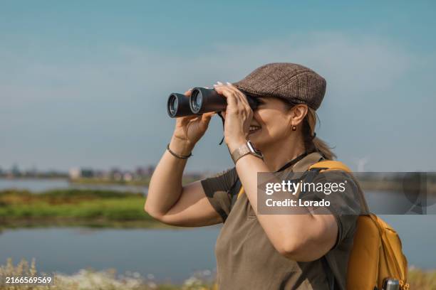 senior birdwatching woman in the netherlands - verrekijker stockfoto's en -beelden