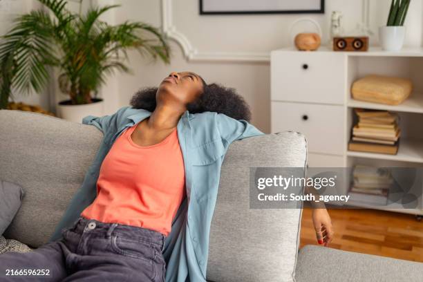 indivíduo relaxado reclinado em um sofá na sala de estar. - devagar - fotografias e filmes do acervo