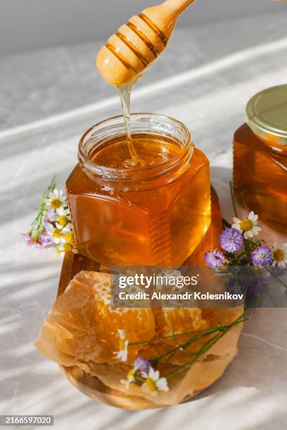healthy organic thick honey dipping from the wooden honey spoon. - honeycomb toffee stock pictures, royalty-free photos & images