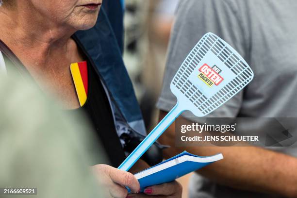 Supporter holds a fly swatter with the slogan 'The east is doing it' of Germany's far-right Alternative for Germany party during an election campaign...