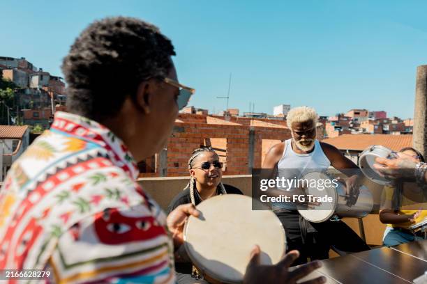 friends playing musical instruments during party on rooftop - tambourine stock pictures, royalty-free photos & images