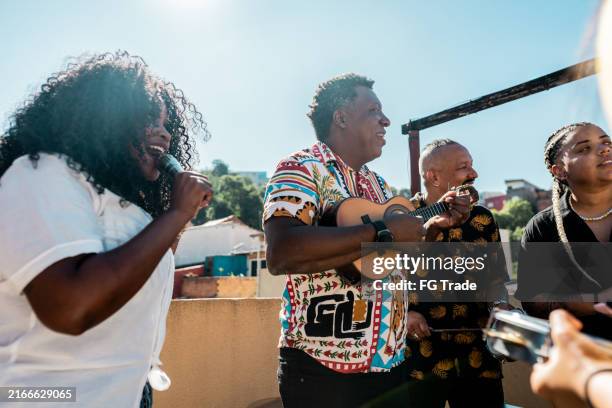 amigos cantando y tocando instrumentos musicales durante la fiesta en la azotea - samba fotografías e imágenes de stock