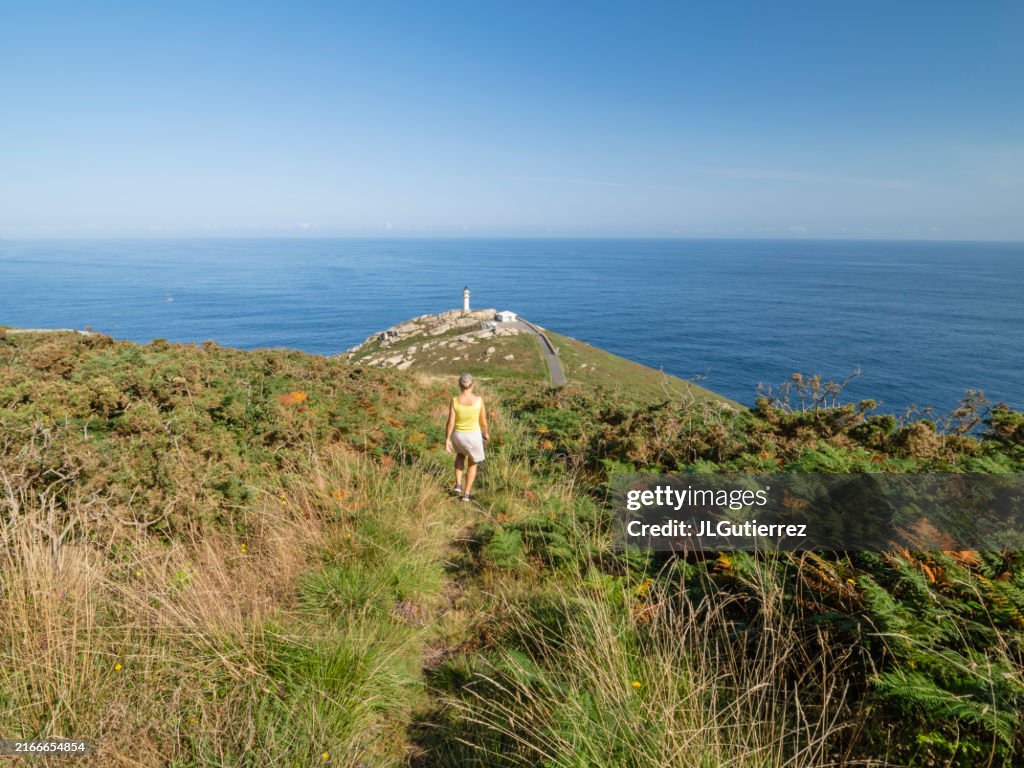 Woman walking towards the Lighthouse at Punta Roncadoira, Lugo coast, Autonomous Community of Galicia