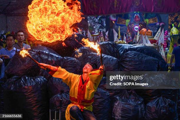 An ethnic Chinese priest blows flames as he performs the prayer ritual "Breaking the Hell's Gate" during the Hungry Ghost festival at Kota Damansara....