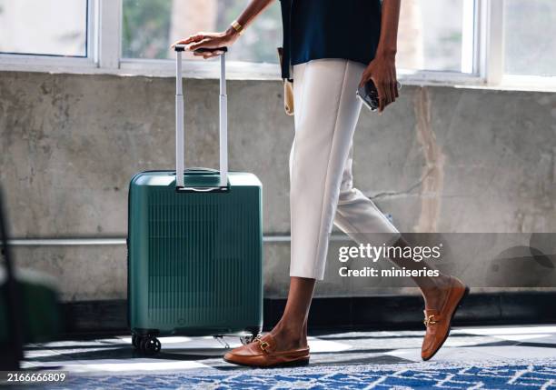 businesswoman walking with suitcase in urban setting - hand luggage stock pictures, royalty-free photos & images