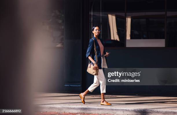 confident businesswoman walking in the city with a smile - black purse stock pictures, royalty-free photos & images
