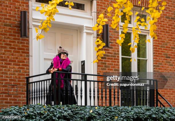 stylish senior woman posing in front of her house, west village, new york city - new york front steps stock pictures, royalty-free photos & images