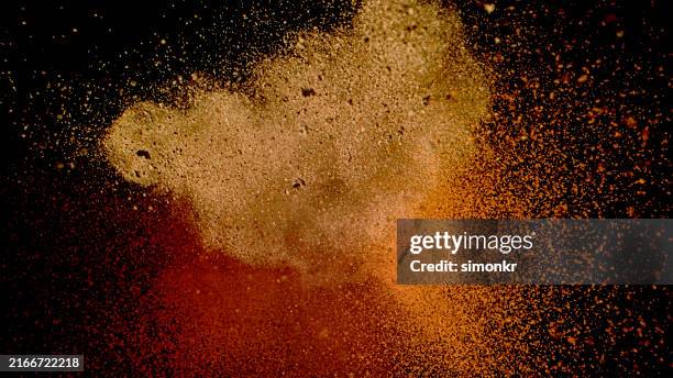 earth-toned particle explosion on black background - powder paint stock pictures, royalty-free photos & images