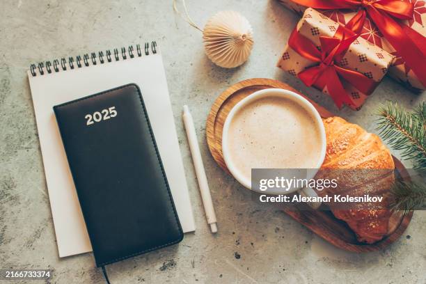 personal organizer for 2025 year, ring binder, coffee cup croissant, gift boxes and holiday decoration on concrete background. high angle view. concept of new year planning - agenda foto e immagini stock