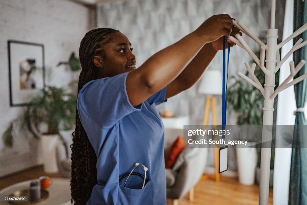 Nurse placing badge on a coat rack in a cozy room