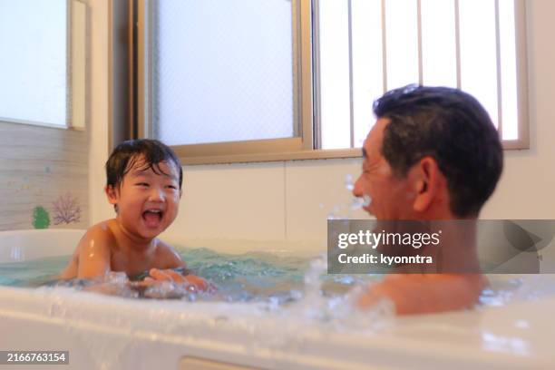 child enjoying a bath with his family - old man bathtub stock pictures, royalty-free photos & images