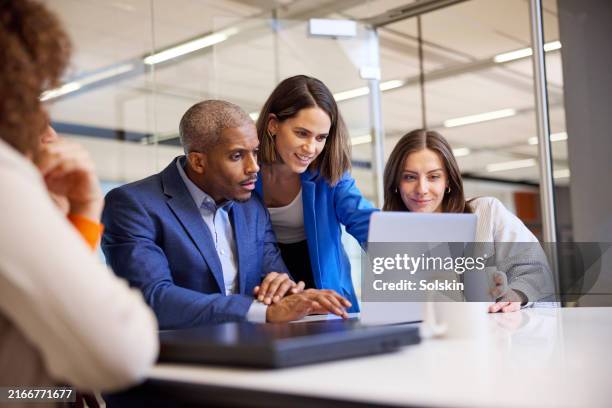 people in modern office meeting room looking at laptop together - riunione commerciale foto e immagini stock