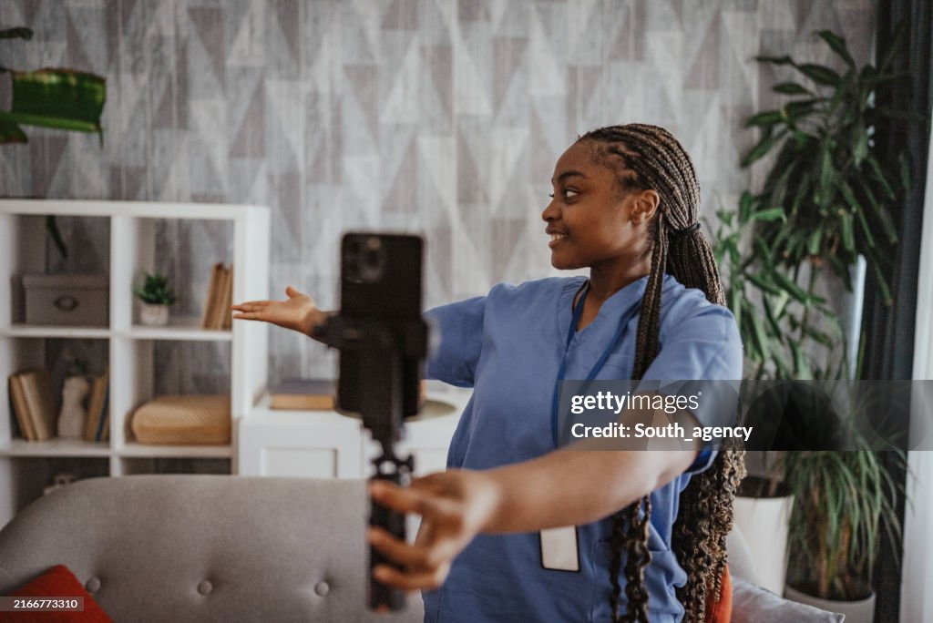 Person in scrubs filming selfie video with camera.