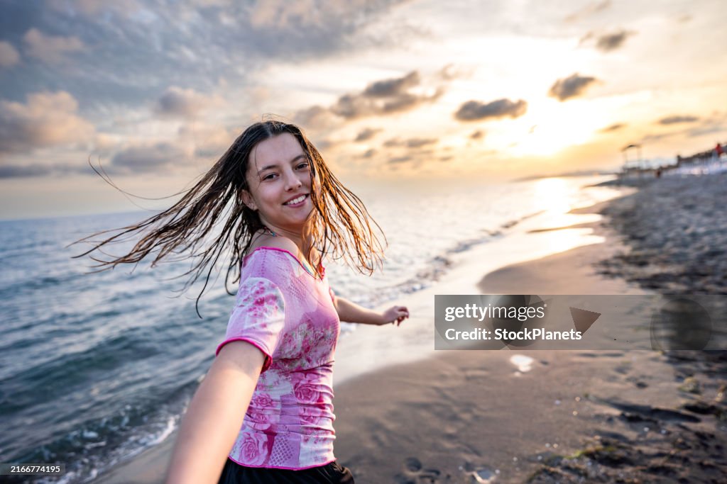 Joyful teenage girl spinning on the beach