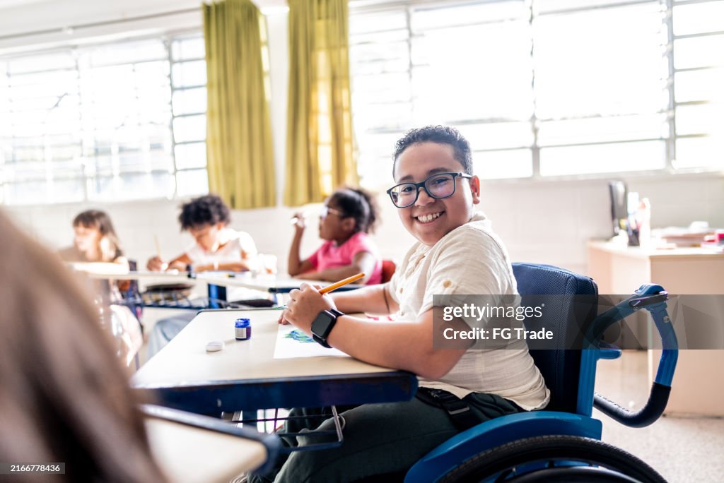 Portrait of a wheelchair student painting on classroom at school