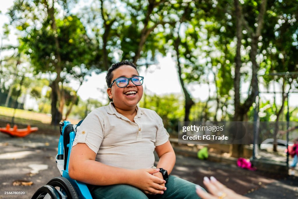 Estudante feliz da cadeira de rodas no campo de jogos da escola