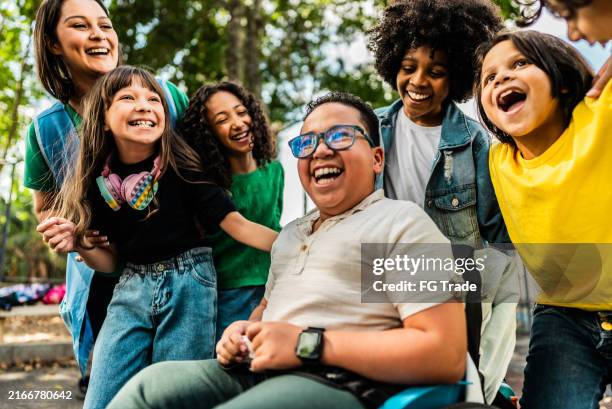 happy students on schoolyard - students-hugging-teacher stock pictures, royalty-free photos & images