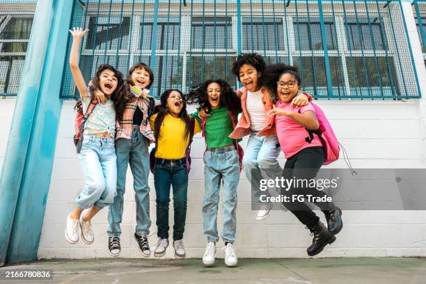 portrait of a students jumping on schoolyard - student wellbeing stock pictures, royalty-free photos & images