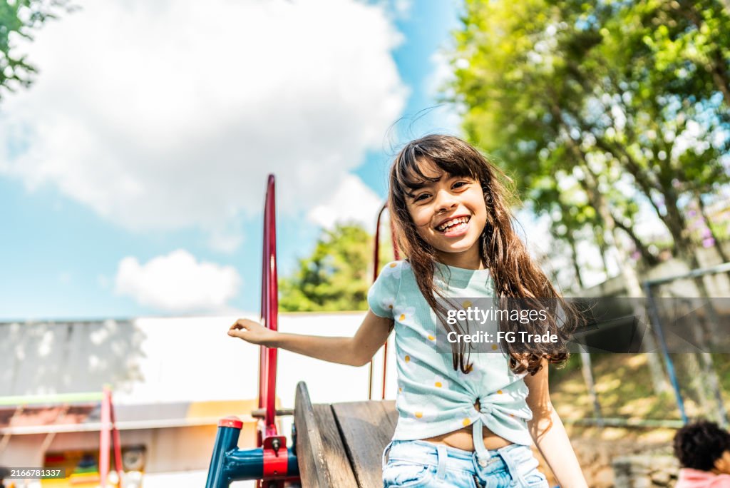 Portrait of a schoolboy playing on slide on school playground