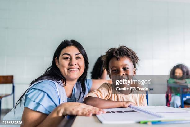 portrait of teacher and student on classroom at school - schooljongen stockfoto's en -beelden