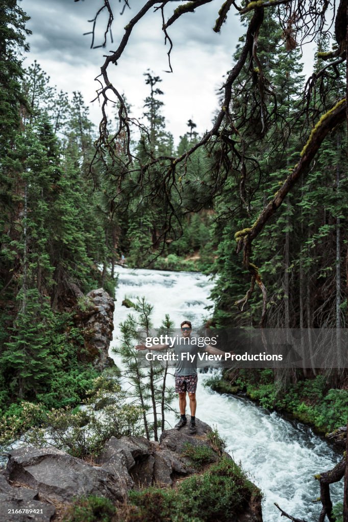 Male hiker poses in front of beautiful river rapids