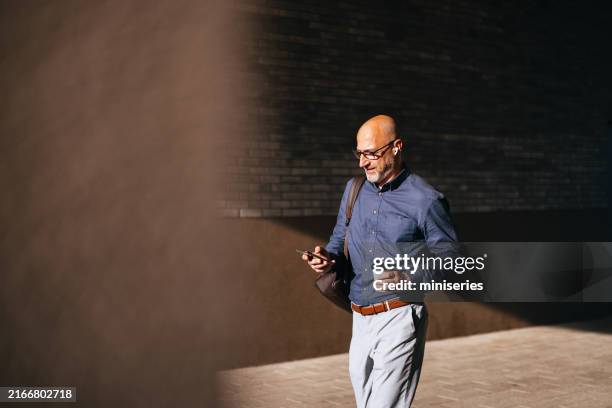 businessman walking in city holding coffee and smartphone - speed walking stock pictures, royalty-free photos & images
