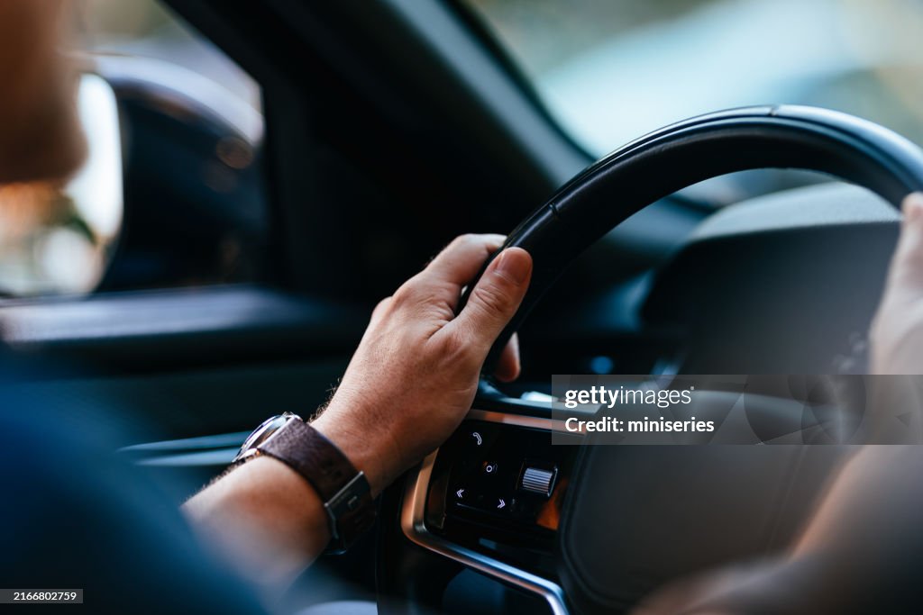 Businessman Driving Car Through City Streets