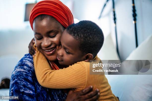 smiling african mom being kissed by her son - boys kissing stock pictures, royalty-free photos & images