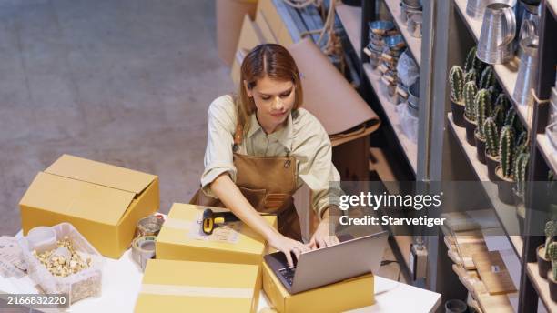 the grocery store warehouse manager working on laptop for confirm the delivery address for delivery after she 'd gotten the online order in the laptop at grocery store. - cost effective stock pictures, royalty-free photos & images