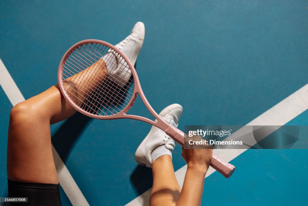 Person, die auf einem Tennisplatz sitzt und einen Schläger hält