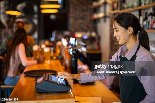 woman using a digital cash register in a pub - cash register stock pictures, royalty-free photos & images