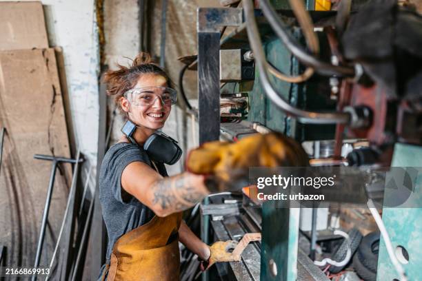 young woman bending metal on machine in a workshop - empreiteiro de reparações imagens e fotografias de stock