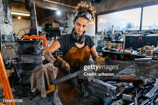 Junge Frau, Die In Einer Werkstatt An Einem Dünnen Metallstab Arbeitet Junge Frau, Die In Einer Werkstatt An Einem Dünnen Metallstab Arbeitet