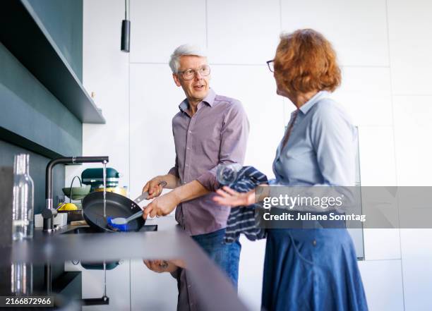Symbolic photo. A man stands in the kitchen and washes dishes on August 13, 2024 in Berlin, Germany.