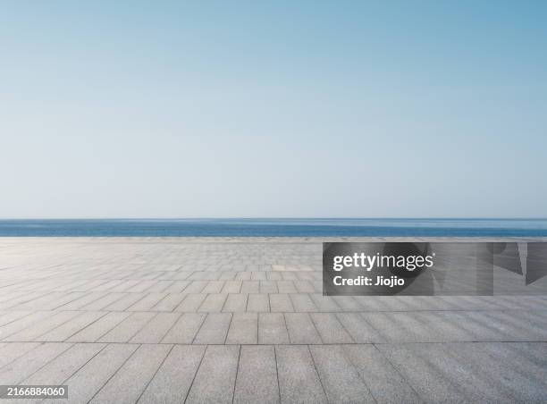 empty road against sea - in bodenhöhe stock-fotos und bilder