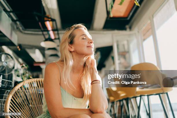 portrait of a beautiful middle-aged woman in a beach cafe in hot summer weather - sleeveless stock pictures, royalty-free photos & images