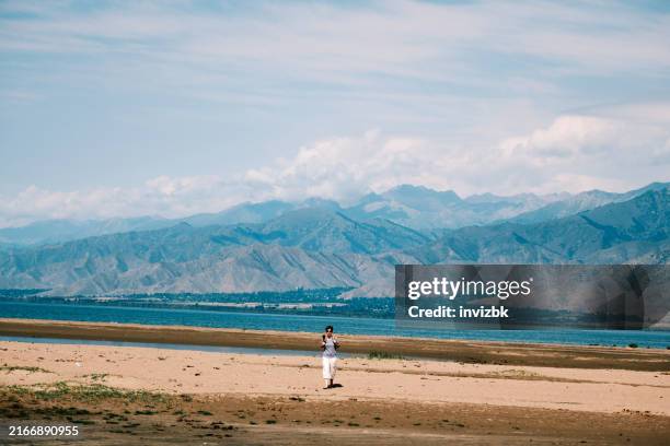 weibliche touristin von 47 jahren ist am strand von salt lake - see issyk kul stock-fotos und bilder