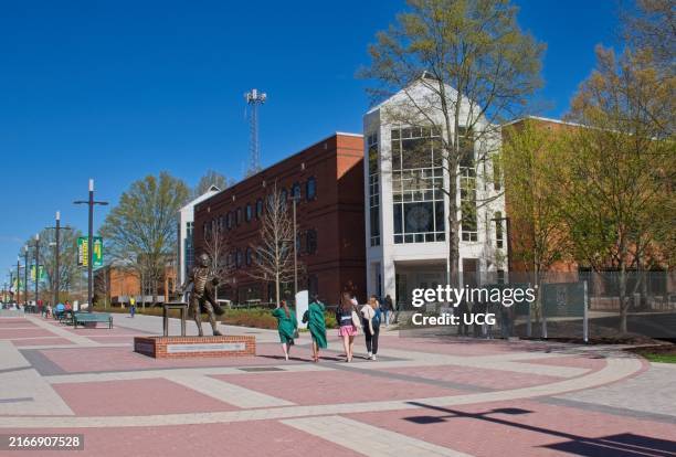 Graduates pass a statue of George Mason on the campus of George Mason University, Fairfax, Virginia.