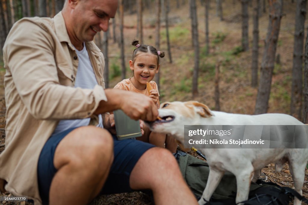 Father and daughter giving a cookie to a dog