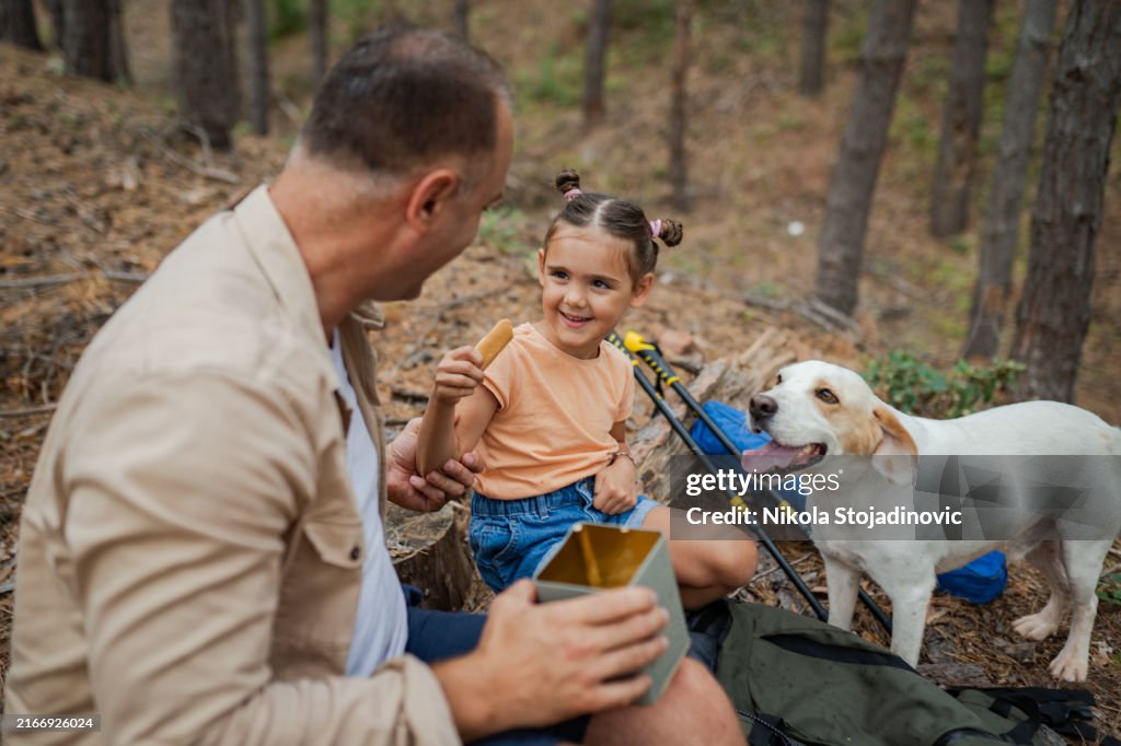 Father and daughter giving a cookie to a dog