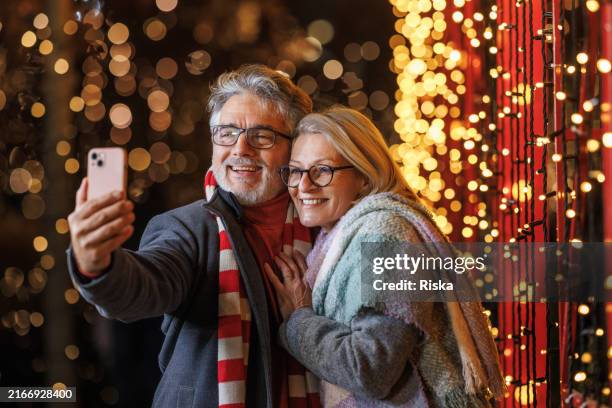 feliz pareja madura tomándose una selfie durante una salida festiva de navidad - mensaje de móvil fotografías e imágenes de stock