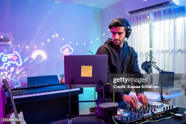 caucasian young man artist dj mixing and scratching music mixer controller. attractive male musician dj having fun mixing music on console touching buttons and playing electronic music at neon party. - dj de club fotografías e imágenes de stock