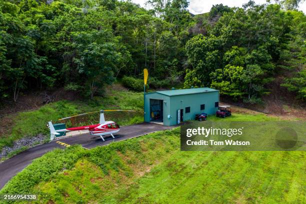 helicopter parked near private hangar in cairns surrounded by lush greenery - cairns australië stockfoto's en -beelden